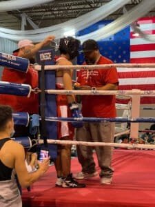 Boxing coach giving instructions to fighter in boxing ring.