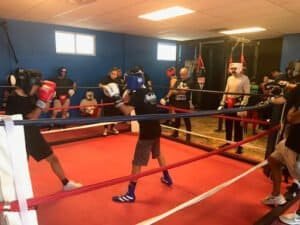 Boxers training in a boxing gym with coaches and equipment.