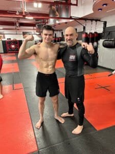 Young fighter and instructor posing in martial arts gym.