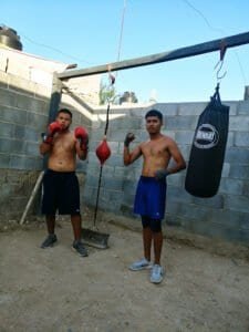 Two young boxers training with gloves and punching bag at Modo Bestia boxing club.