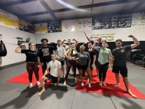Group of diverse people flexing muscles in a gym class at Ignite Fitness Lafayette.