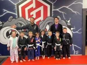 Kids and coaches in martial arts uniforms at Gladiators Academy of Crowley.