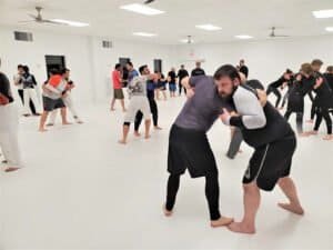 Students practicing martial arts techniques in a spacious training room.