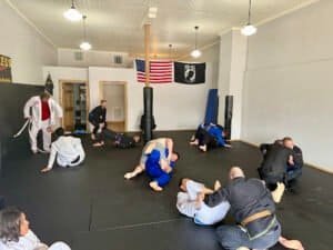 Students practicing Brazilian Jiu-Jitsu techniques in a training session.