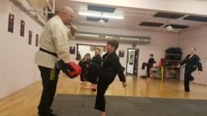 Martial arts instructor teaching a young student in a dojo.