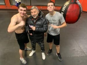 Young boxers with coach in gym, preparing for a match.