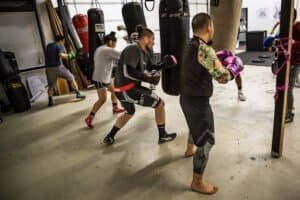 Group of fighters practicing boxing techniques in a gym.