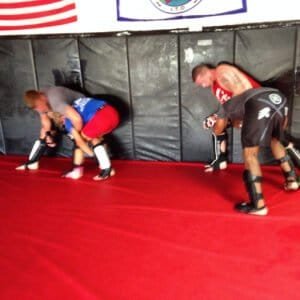 MMA fighters practicing ground techniques in training session.