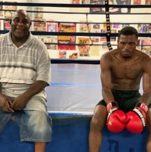 Young boxer with red gloves sitting in boxing ring after training session.