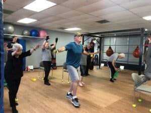 People participating in a fitness class with weights and balls at 413 FITNESS.