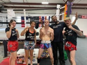Group of Thai boxing fighters and trainers in the gym.