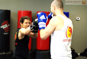 Martial arts training with a woman and man practicing boxing techniques.