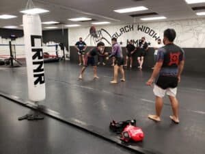MMA fighters practicing grappling techniques at Black Widow MMA gym.