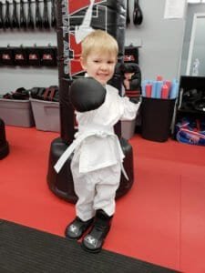 Young boy in karate gi with gloves in martial arts training center.