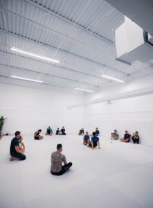 Group of people practicing martial arts in a bright, spacious gym.