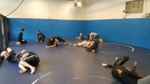 Mixed martial arts training with multiple fighters practicing grappling and ground techniques.