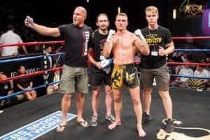 Muay Thai fighter with team after match in the ring.