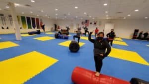 Students practicing martial arts techniques in a spacious training facility.