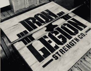 Barbell with weights on a wooden platform at Iron Legion Strength Co.