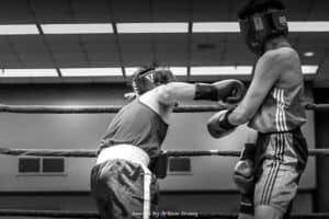 Two young boxers sparring in a boxing ring during training session.