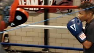 Young boxer practicing punch with focus mitts in Cleveland boxing gym.