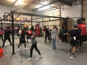 Boxers training with punching bags at Peña Boxing Club gym.