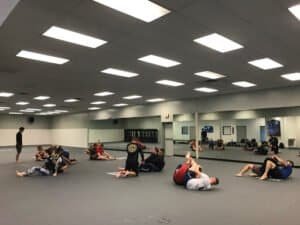Group of people practicing MMA techniques in a spacious gym.