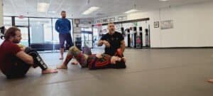 Instructor demonstrating techniques to students in a Brazilian Jiu-Jitsu class.