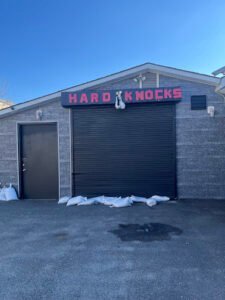 Exterior view of Hard Knocks Boxing Gym with closed garage door.