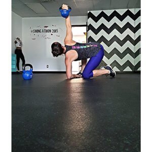 Woman performing kettlebell exercise during fitness class at KettleBella Fitness.