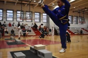 Young martial artist performing high kick during training session.