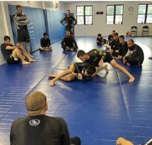 BJJ students practicing grappling techniques in a training room.