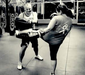 Female boxer practicing kickboxing with trainer at CKO Kickboxing gym.