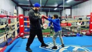 Young boy practicing boxing with coach in Montoya Boxing Gym.