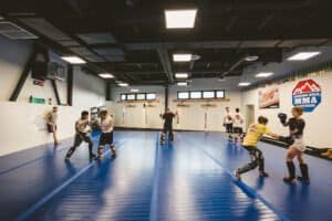MMA fighters practicing striking and grappling in a spacious gym.