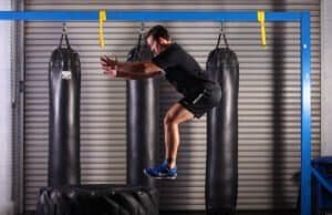 Man jumping on a punching bag during boxing workout at gym.