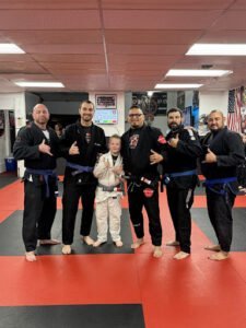Group of martial artists and a young student in Brazilian Jiu Jitsu gi.