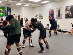 Martial arts fighters practicing Brazilian Jiu-Jitsu and MMA techniques in training gym.