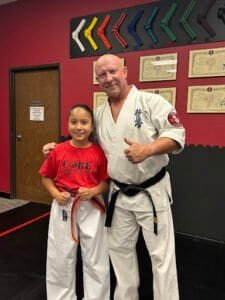 Young girl and instructor in martial arts uniform at Core Martial Arts & Fitness.