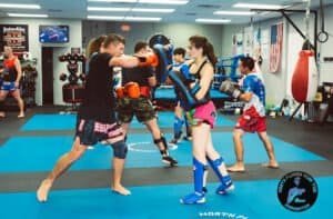 Kids and adults practicing Muay Thai boxing in a gym.