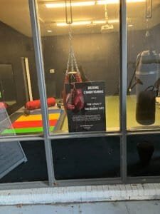 Boxing punching bag and training gear in gym window display.