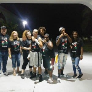 Group of diverse boxers and supporters at night, wearing LBP Boxing shirts.